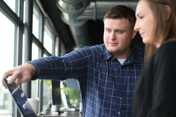 A man points at a computer screen as the woman beside him looks on