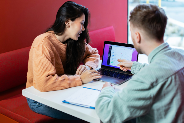 A man and woman are looking at laptop, smiling.